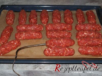 Die Hackfleischröllchen auf einem Backblech (mit Kerntemperaturmesser)