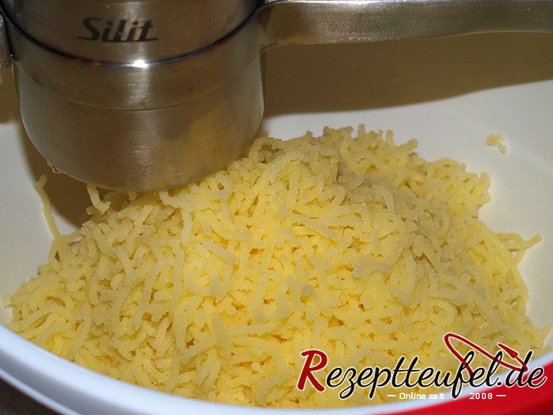 Die abgedämpften Kartoffeln heiß durch eine Kartoffelpresse drücken