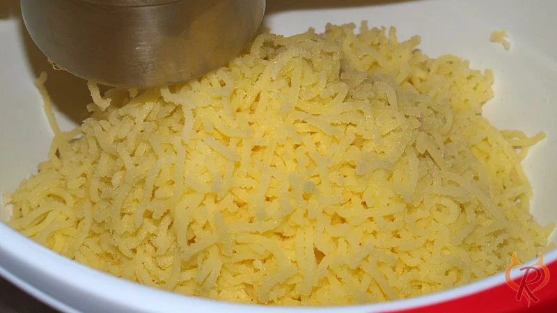 Die abgedämpften Kartoffeln heiß durch eine Kartoffelpresse drücken